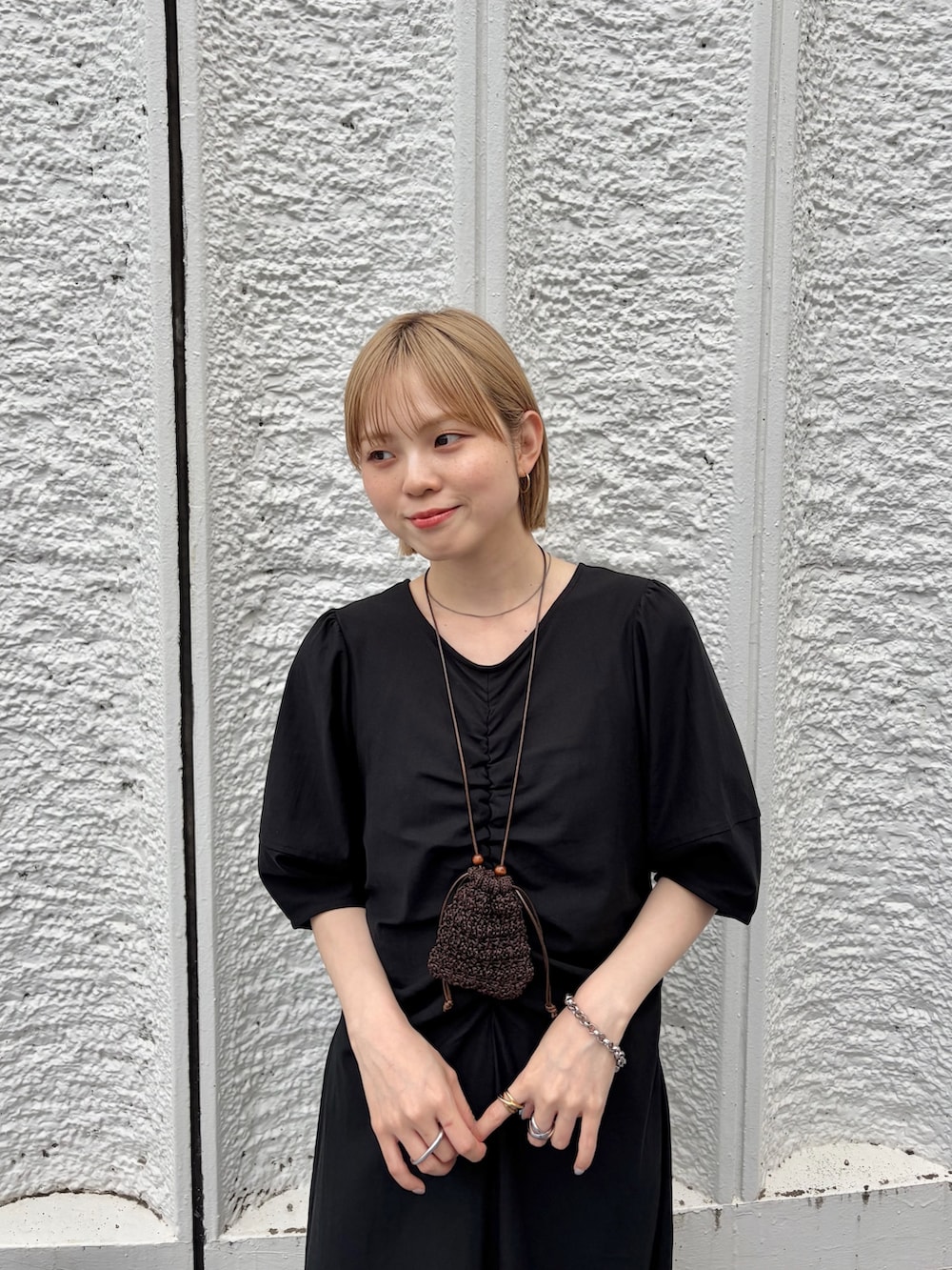 ブラック系のワンピース、ベージュ系のスニーカー、ブラウン系のポーチを着用したレディースの夏コーディネートの4枚目の写真