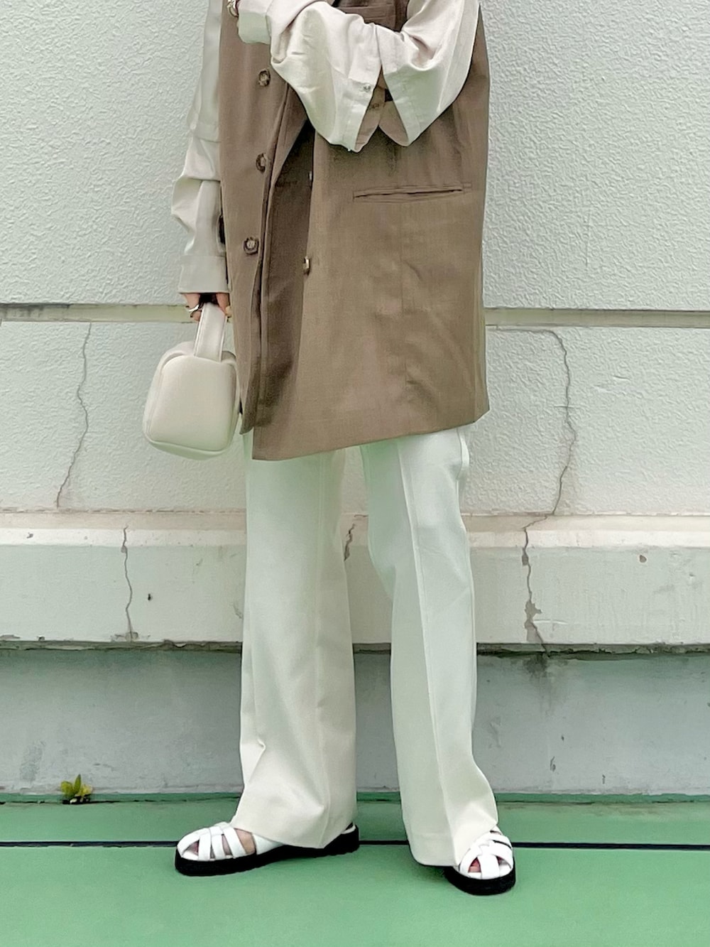 ブルー系のベスト、ホワイト系のハンドバッグ、ブラウン系のシャツ/ブラウスを着用したレディースの春コーディネートの2枚目の写真