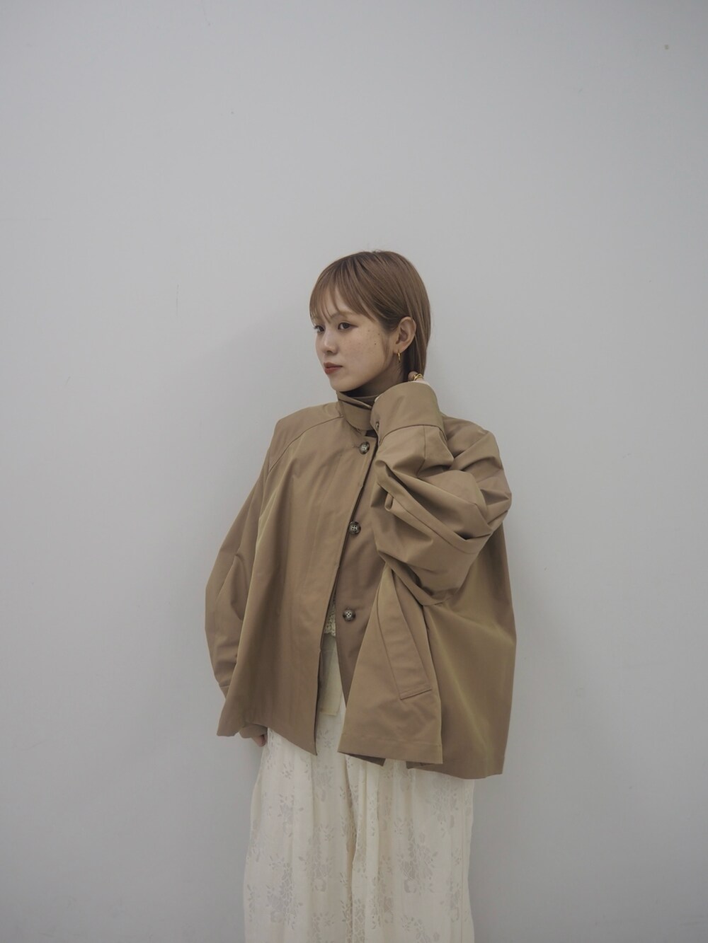 ベージュ系のステンカラーコート、ホワイト系のその他パンツ、ブラウン系のその他シューズを着用したレディースの冬コーディネートの4枚目の写真