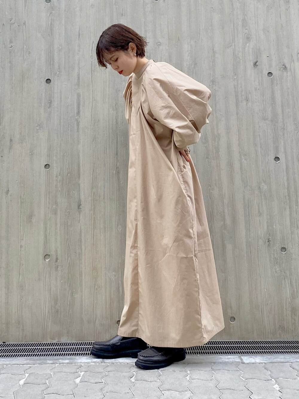 グレー系のブーツ、ベージュ系のワンピース、ピンク系のカーディガン/ボレロを着用したレディースの春コーディネートの3枚目の写真