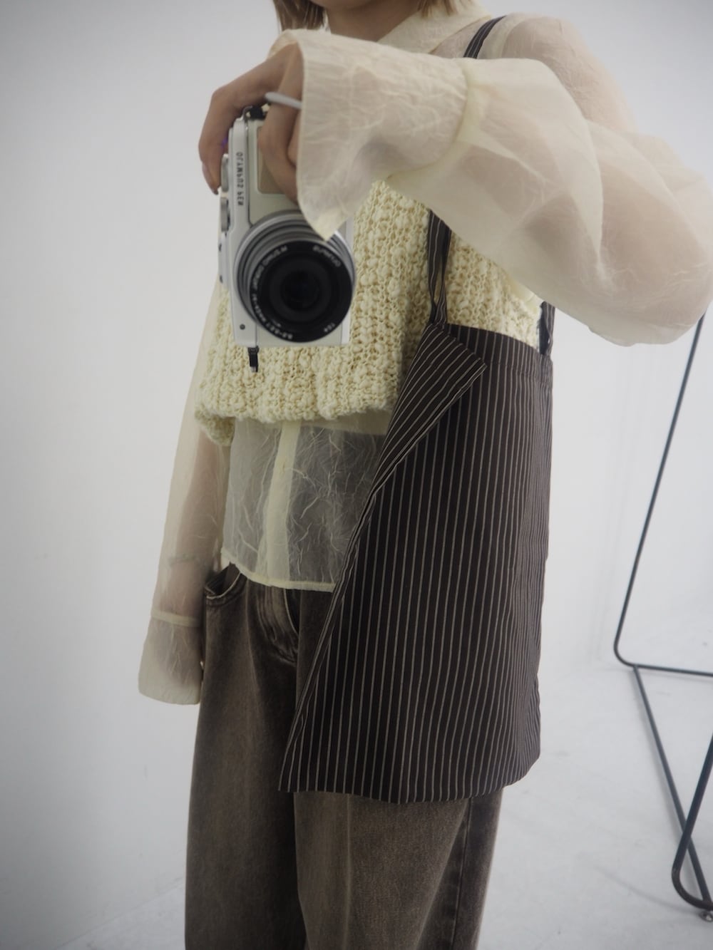 ブラウン系のデニムパンツ、ホワイト系のニット/セーター、ブラック系のその他シューズを着用したレディースの冬コーディネートの2枚目の写真