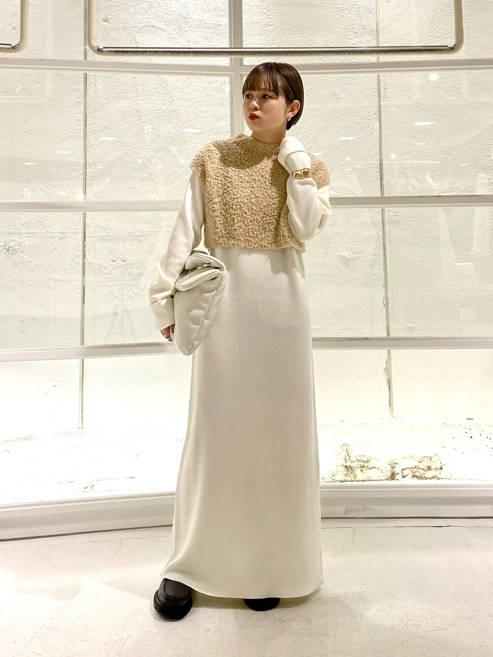 グレー系のブーツ、ホワイト系のワンピース、ブラック系のハンドバッグを着用したレディースの冬コーディネートの2枚目の写真