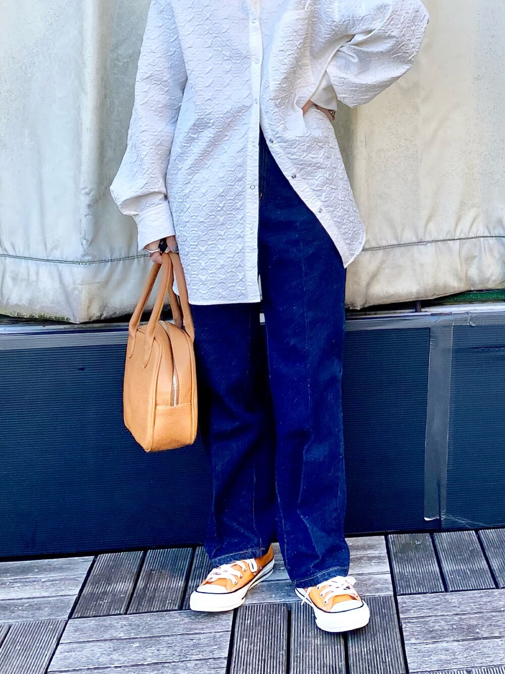 イエロー系のボストンバッグ、オレンジ系のスニーカー、ブルー系のデニムパンツを着用したレディースの冬コーディネートの3枚目の写真