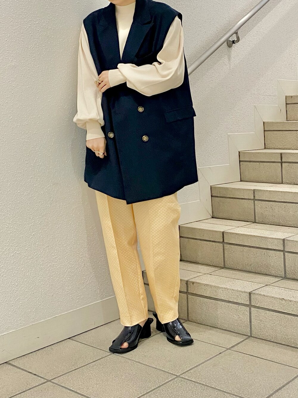 イエロー系のサンダル、イエロー系のその他パンツ、ブルー系のベストを着用したレディースの春コーディネートの2枚目の写真