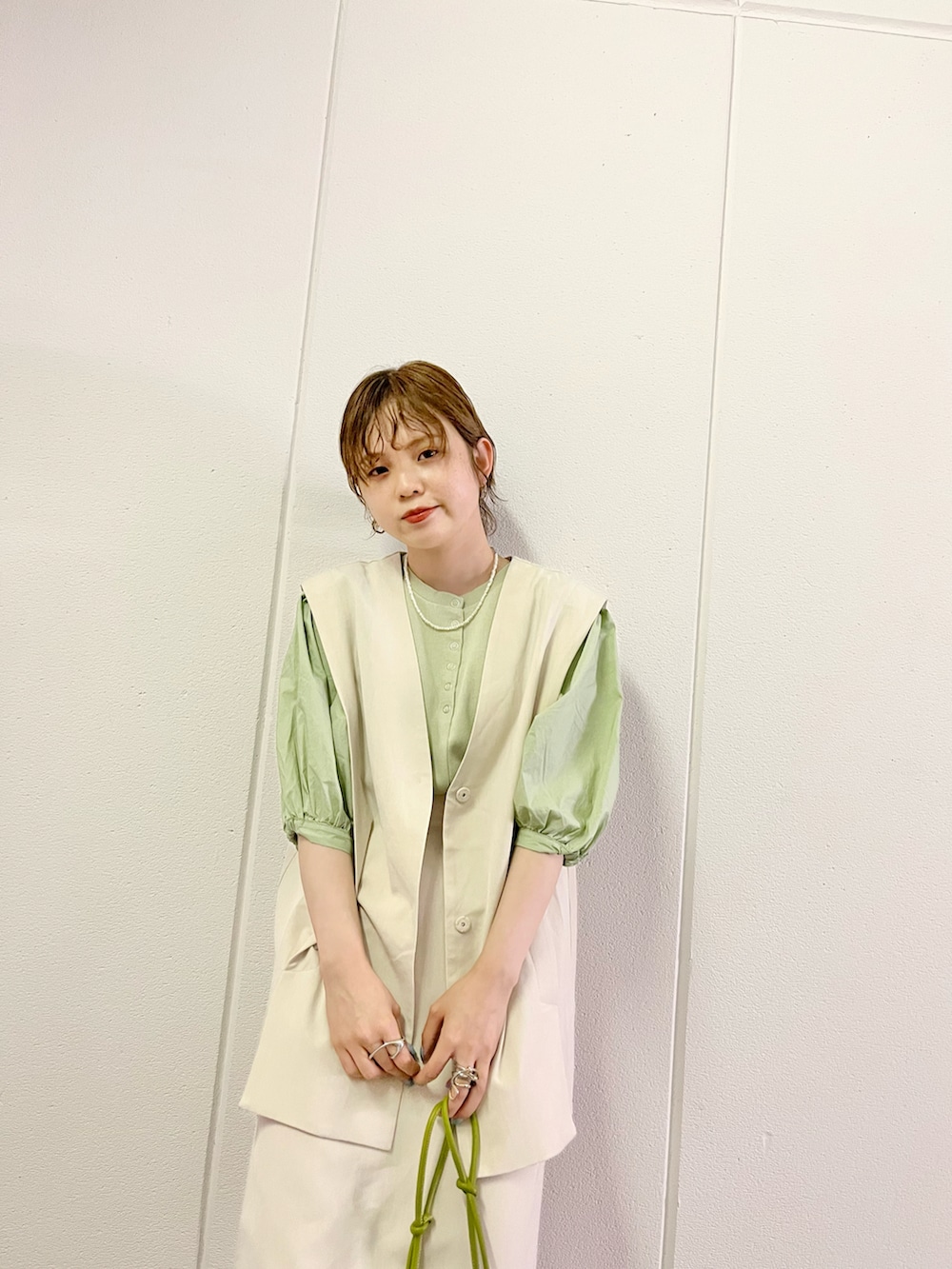 グリーン系のショルダーバッグ、ホワイト系のサンダル、ベージュ系のワンピースを着用したレディースの夏コーディネートの2枚目の写真