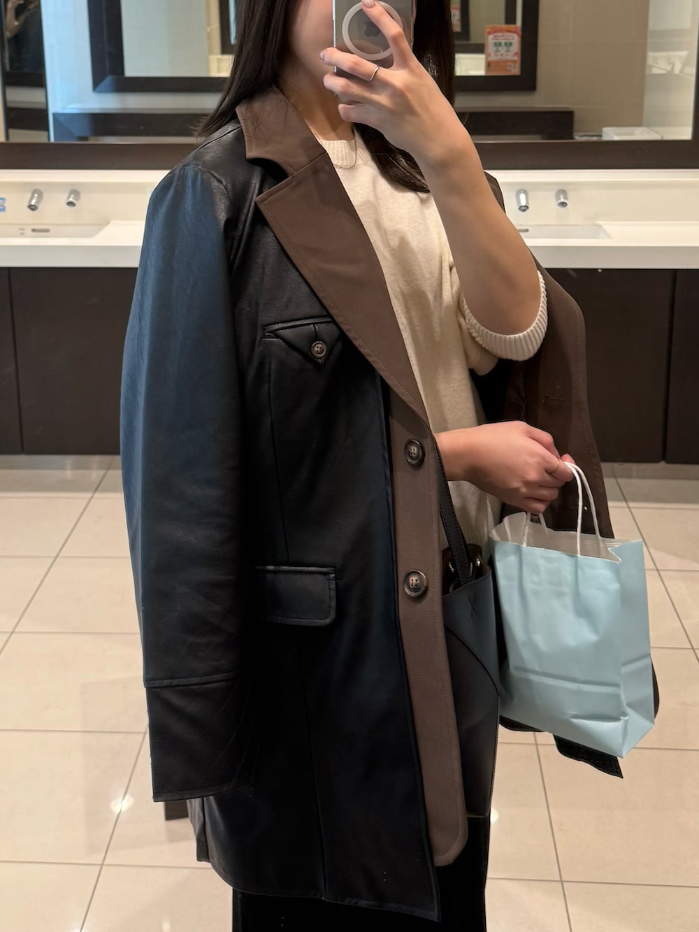 ブラック系のテーラードジャケット、ブラック系のスカート、シルバー系のスニーカーを着用したレディースの冬コーディネートの4枚目の写真