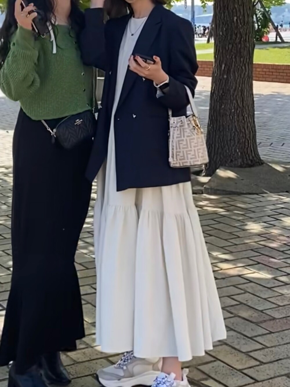 ブルー系のテーラードジャケット、ホワイト系のワンピース、ホワイト系のスニーカーを着用したレディースの春コーディネートの2枚目の写真