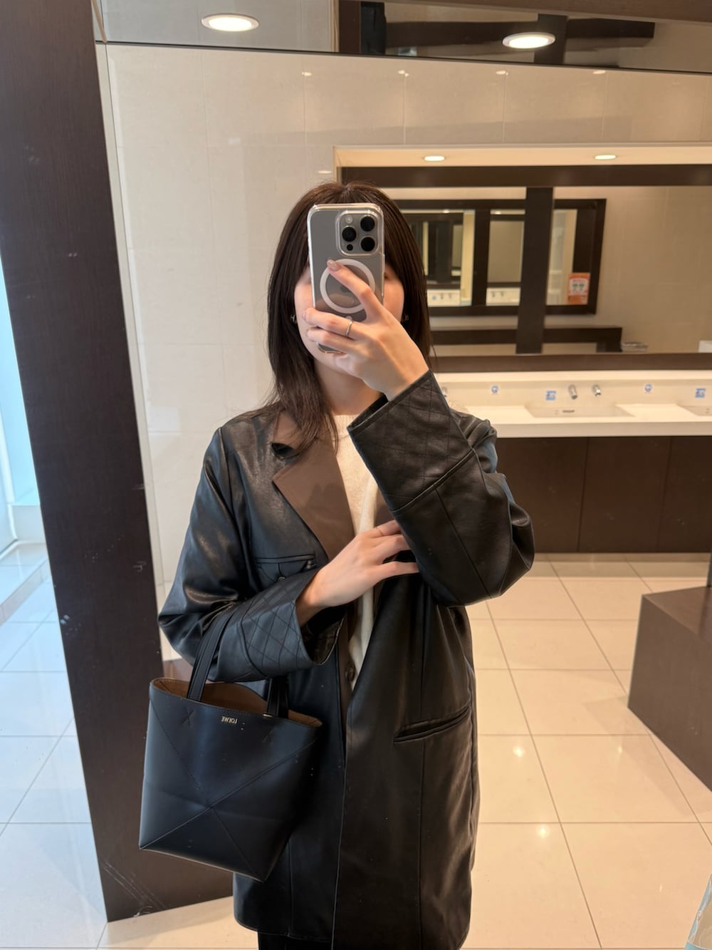 ブラック系のテーラードジャケット、ブラック系のスカート、シルバー系のスニーカーを着用したレディースの冬コーディネートの2枚目の写真