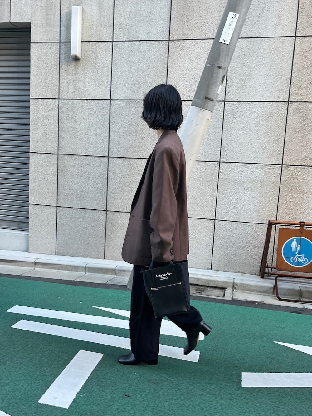 ブラック系のトートバッグ、ブラック系のスラックス、ブラック系のブーツを着用したレディースの秋コーディネートの2枚目の写真