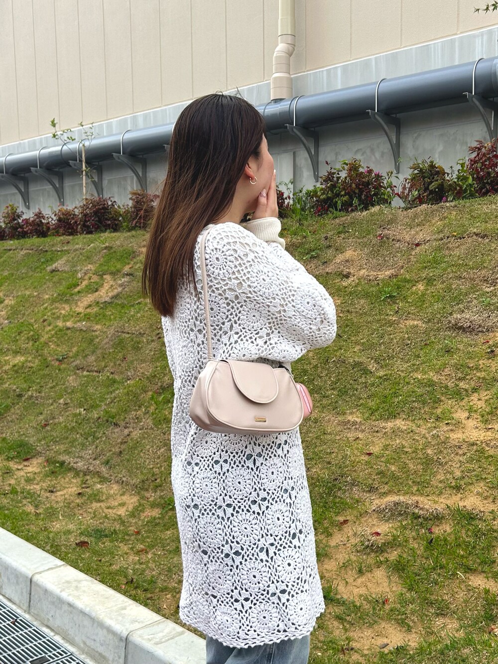 ブルー系のデニムパンツ、ベージュ系のハンドバッグ、ホワイト系のニット/セーターを着用したレディースの春コーディネートの5枚目の写真