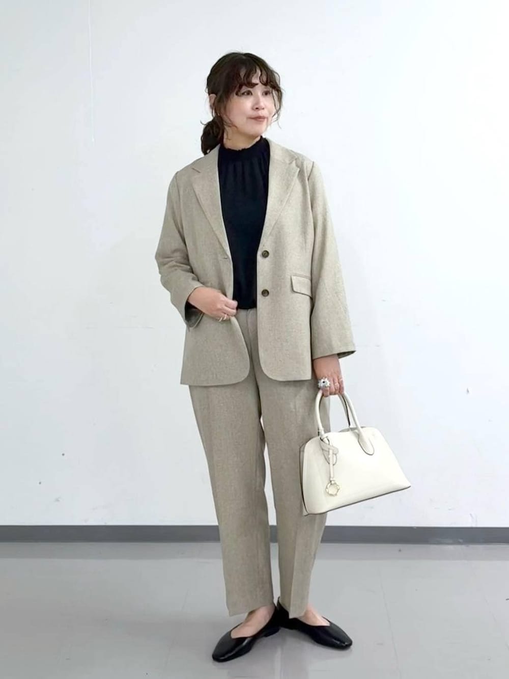 ブラック系のパンプス、ホワイト系のショルダーバッグ、ベージュ系のその他パンツを着用したレディースの春コーディネートの2枚目の写真