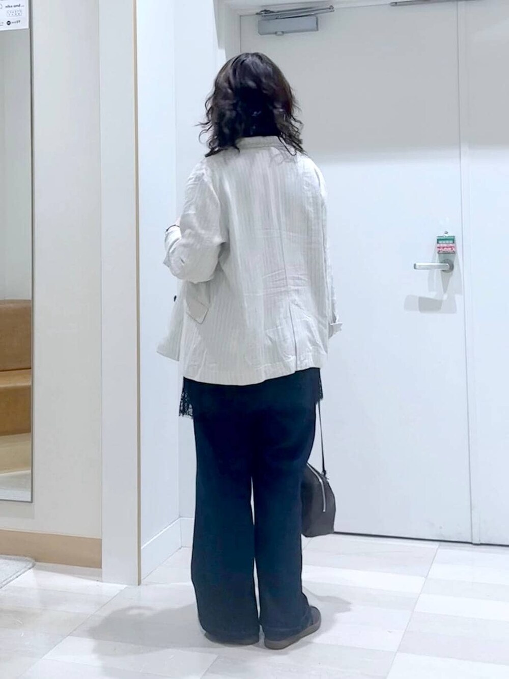 ブルー系のデニムパンツ、グレー系のテーラードジャケット、ブラック系のタンクトップを着用したレディースの春コーディネートの4枚目の写真