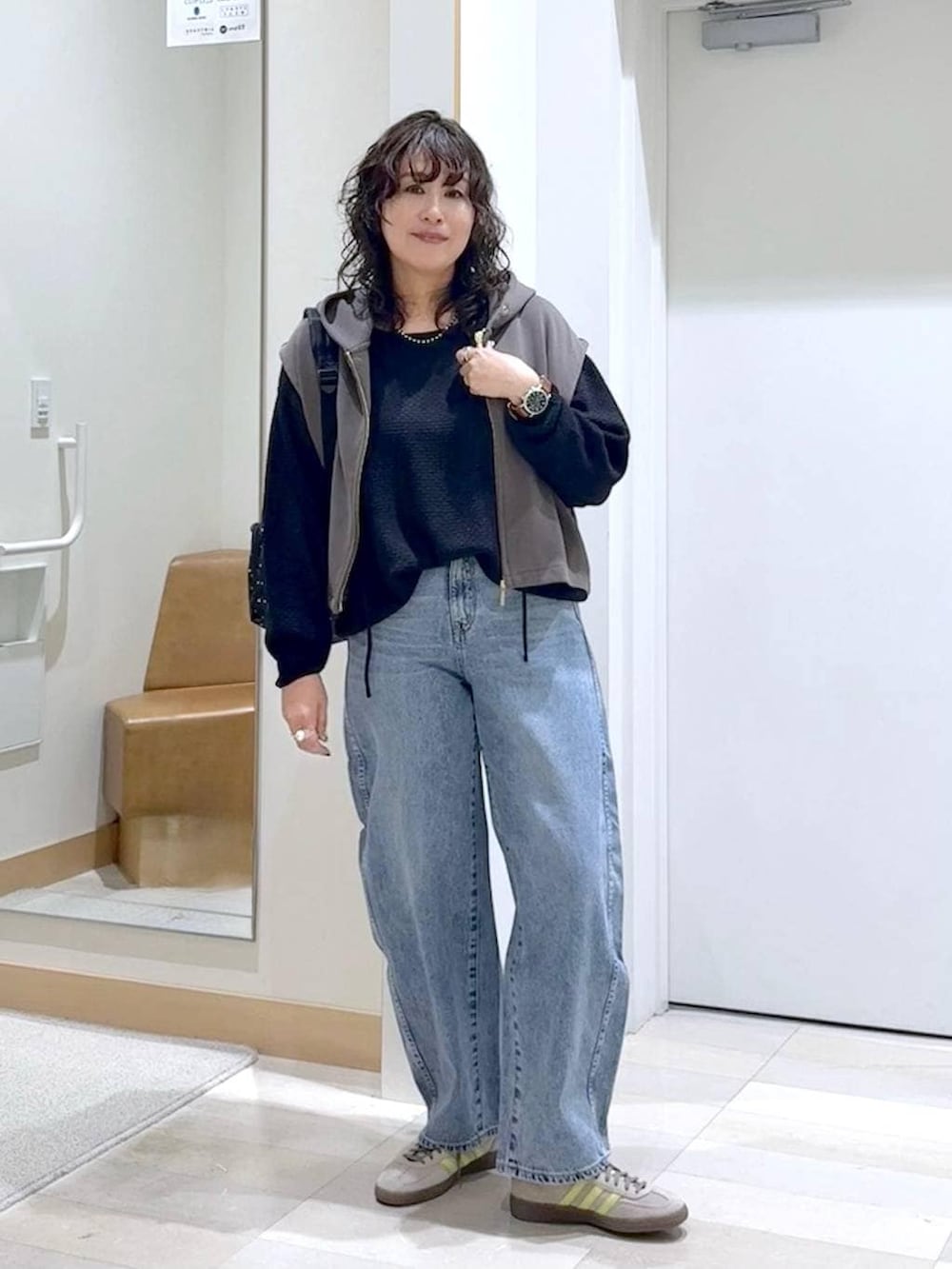 グレー系のバックパック/リュック、ブルー系のデニムパンツ、ブラウン系のベストを着用したレディースの春コーディネートの4枚目の写真