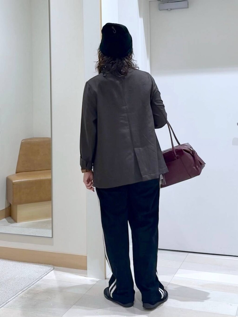 レッド系のボストンバッグ、ブラウン系のテーラードジャケット、グレー系のタンクトップを着用したレディースの秋コーディネートの4枚目の写真