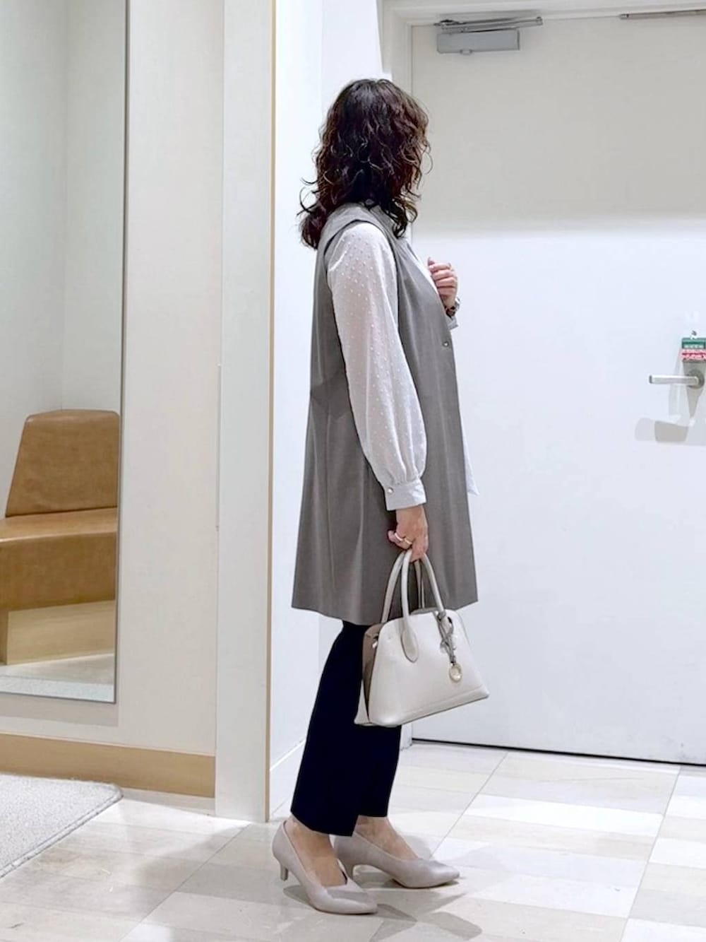 ホワイト系のショルダーバッグ、ホワイト系のパンプス、ブルー系のスラックスを着用したレディースの春コーディネートの3枚目の写真