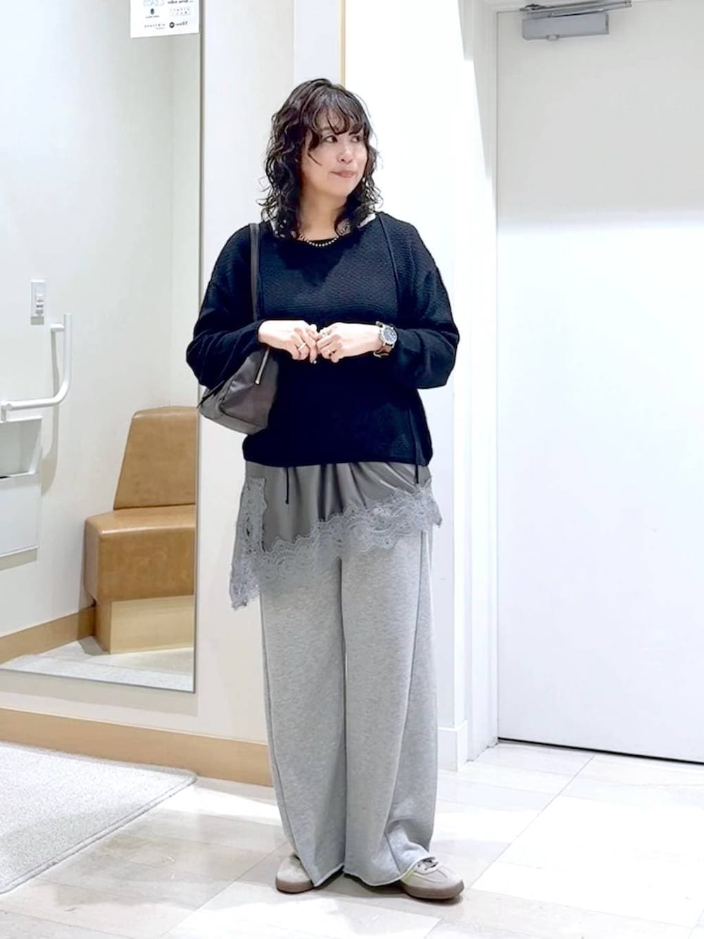 グレー系のスウェットパンツ、ブラック系のタンクトップ、ブラウン系のショルダーバッグを着用したレディースの春コーディネートの2枚目の写真