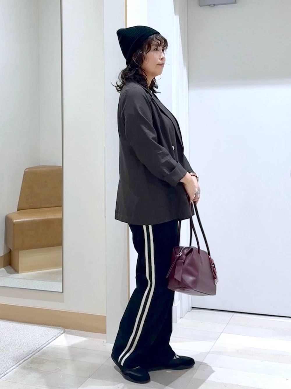 レッド系のボストンバッグ、ブラウン系のテーラードジャケット、グレー系のタンクトップを着用したレディースの秋コーディネートの3枚目の写真