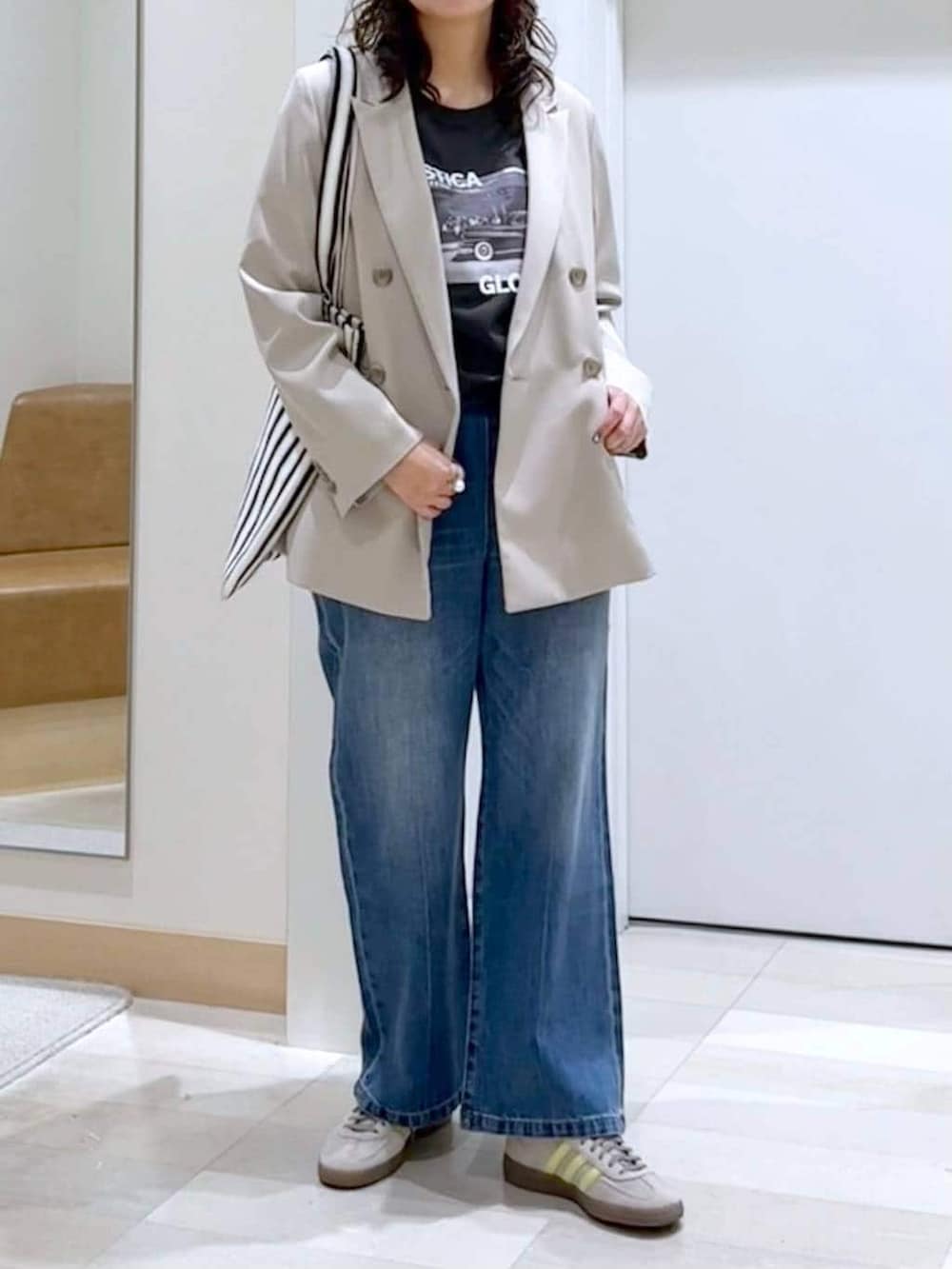 ブルー系のデニムパンツ、ベージュ系のテーラードジャケット、ホワイト系のトートバッグを着用したレディースの春コーディネートの5枚目の写真