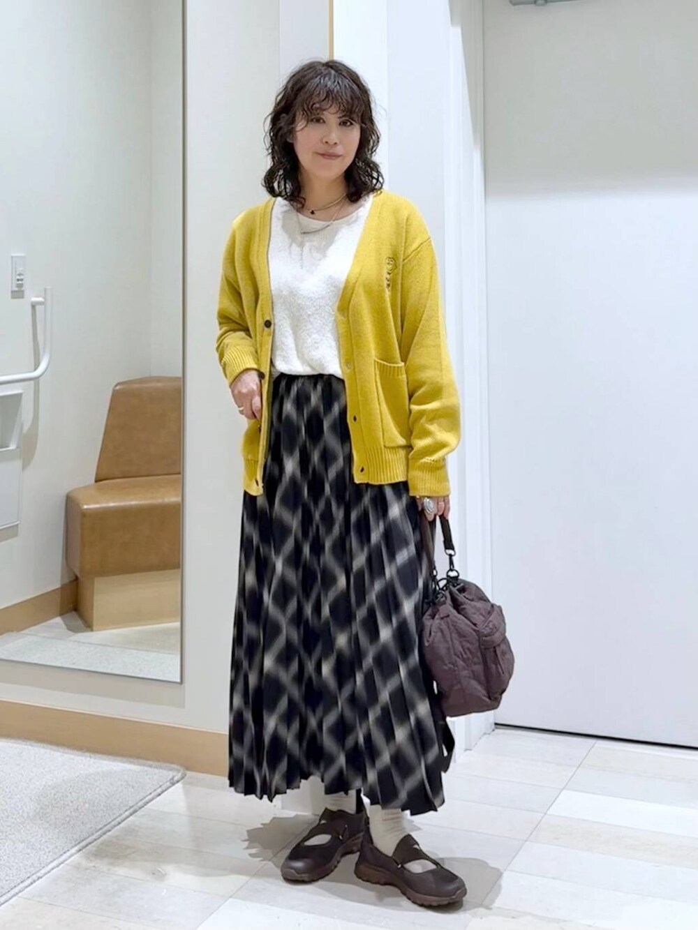 ブラウン系のスニーカー、ベージュ系のニット/セーター、ブラウン系のショルダーバッグを着用したレディースの秋コーディネートの2枚目の写真