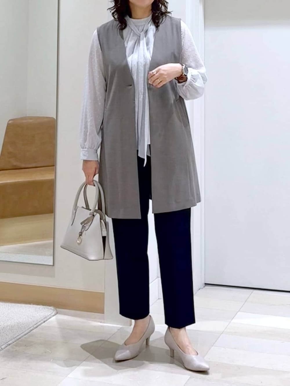 ホワイト系のショルダーバッグ、ホワイト系のパンプス、ブルー系のスラックスを着用したレディースの春コーディネートの5枚目の写真