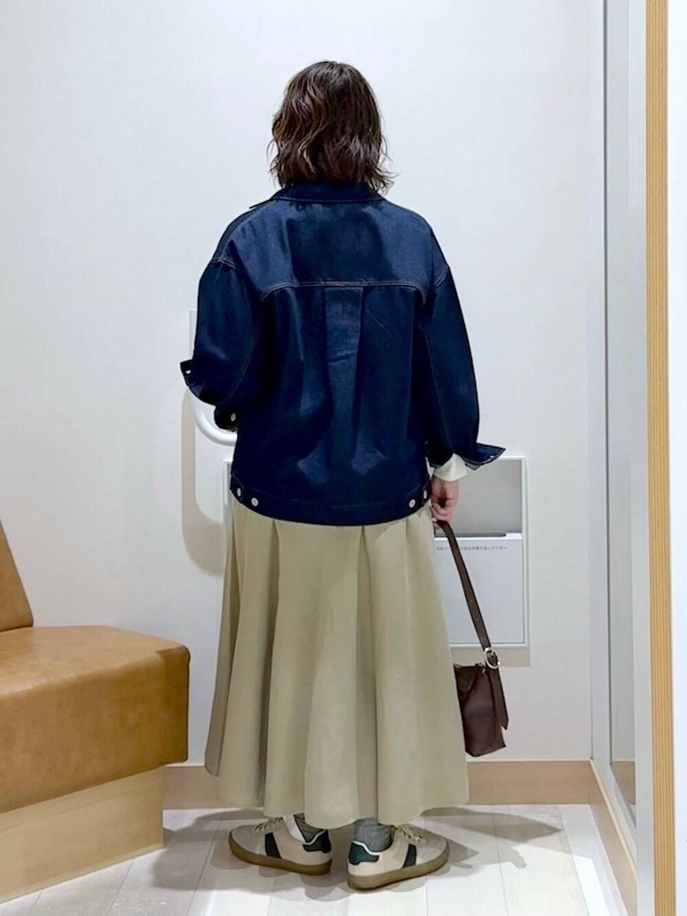 ベージュ系のスニーカー、ブラウン系のショルダーバッグ、ブルー系のデニムジャケットを着用したレディースの春コーディネートの4枚目の写真