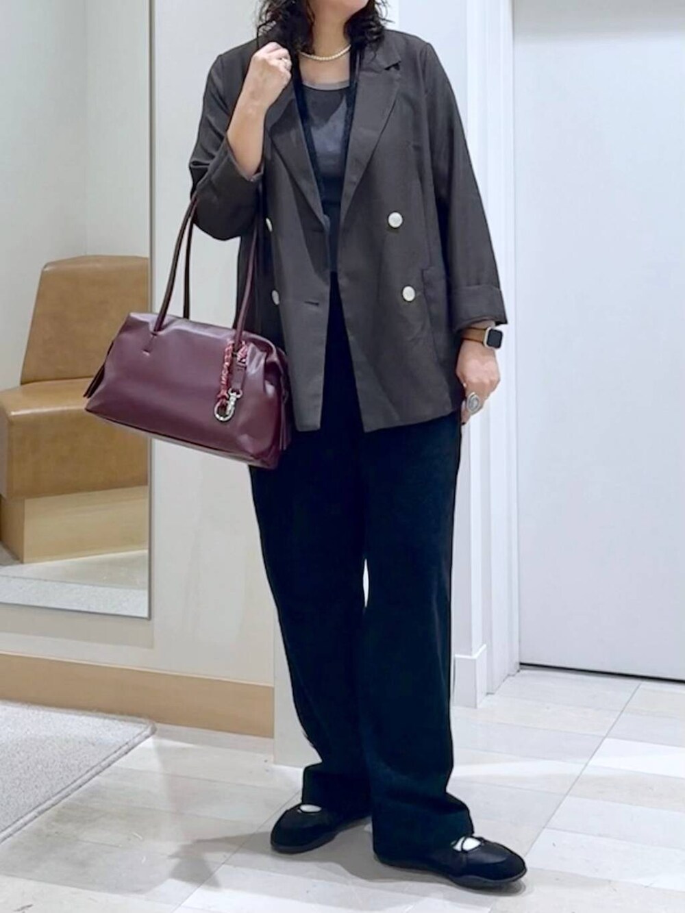 レッド系のボストンバッグ、ブラウン系のテーラードジャケット、グレー系のタンクトップを着用したレディースの秋コーディネートの5枚目の写真