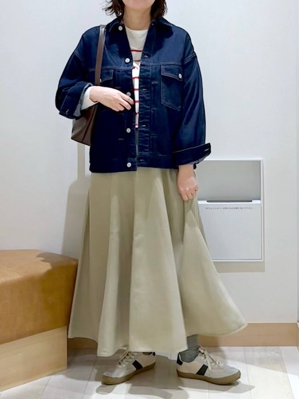 ベージュ系のスニーカー、ブラウン系のショルダーバッグ、ブルー系のデニムジャケットを着用したレディースの春コーディネートの5枚目の写真