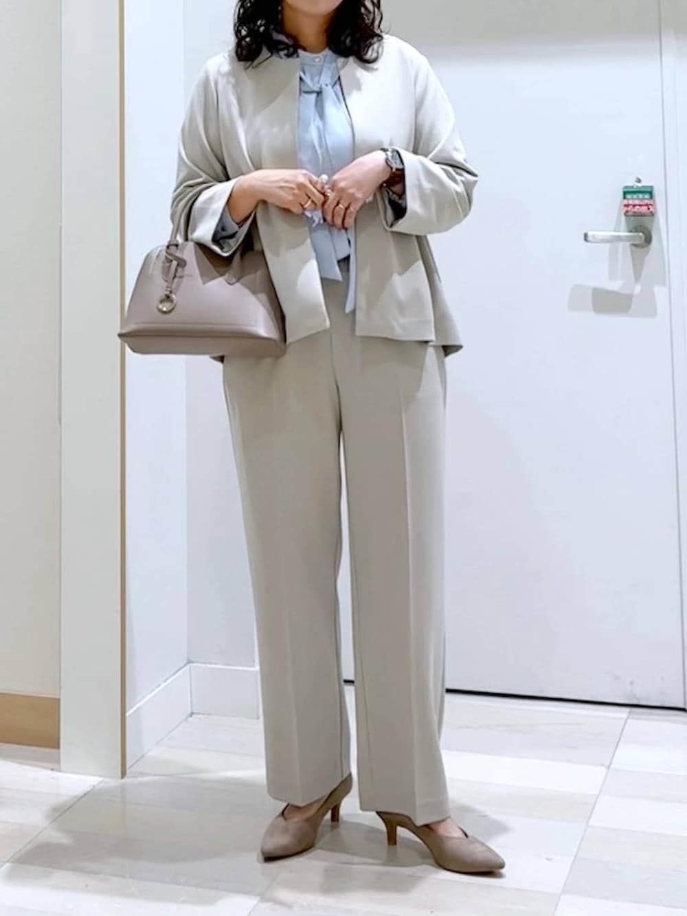 ベージュ系のショルダーバッグ、ベージュ系のパンプス、ブルー系のシャツ/ブラウスを着用したレディースの春コーディネートの5枚目の写真