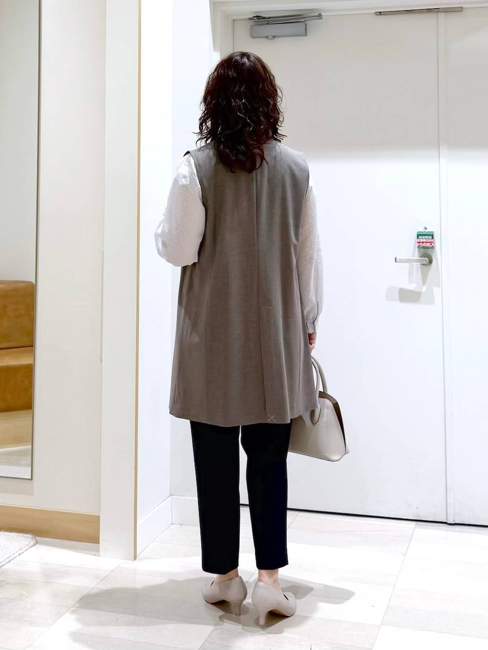 ホワイト系のショルダーバッグ、ホワイト系のパンプス、ブルー系のスラックスを着用したレディースの春コーディネートの4枚目の写真