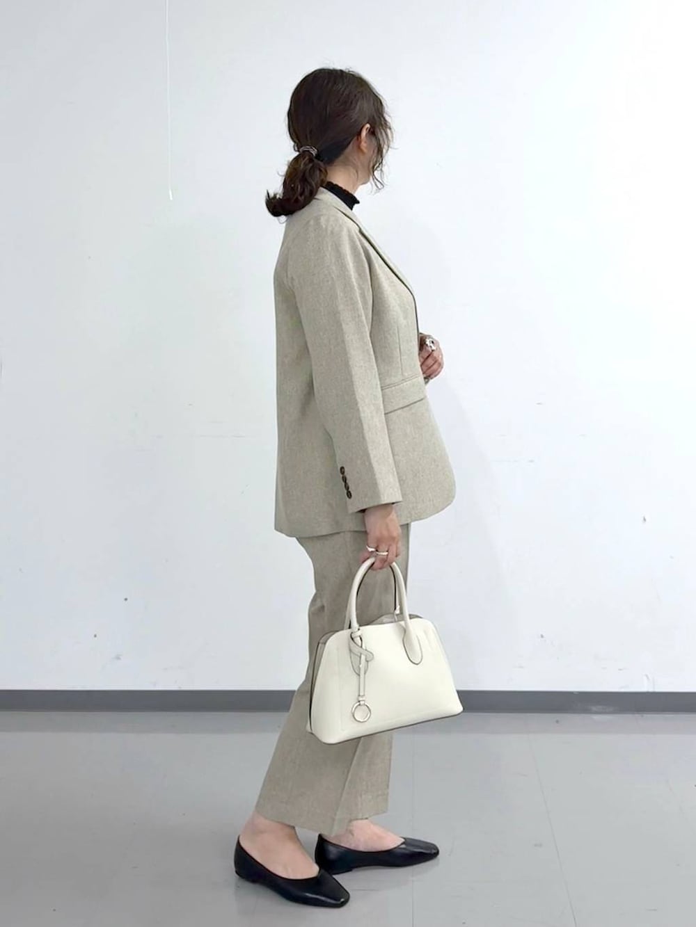 ブラック系のパンプス、ホワイト系のショルダーバッグ、ベージュ系のその他パンツを着用したレディースの春コーディネートの3枚目の写真