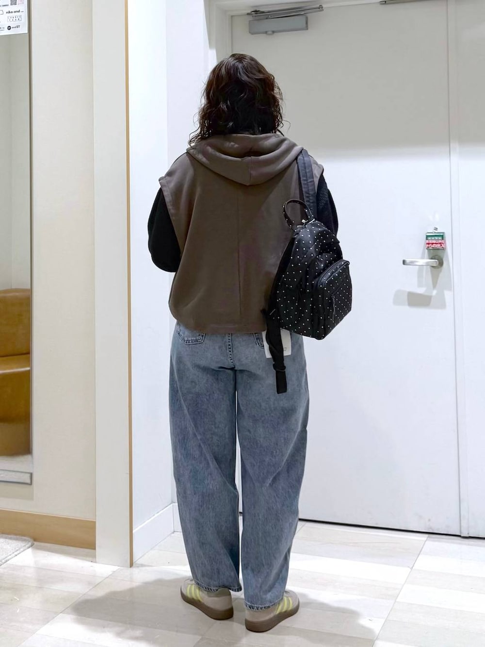 グレー系のバックパック/リュック、ブルー系のデニムパンツ、ブラウン系のベストを着用したレディースの春コーディネートの3枚目の写真