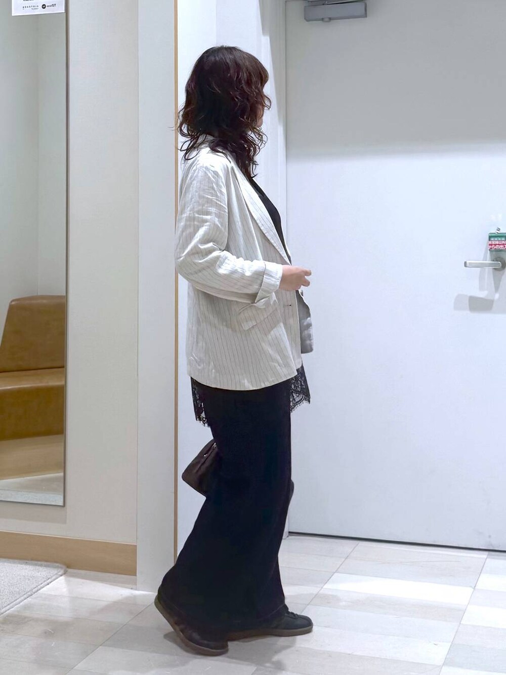 ブルー系のデニムパンツ、グレー系のテーラードジャケット、ブラック系のタンクトップを着用したレディースの春コーディネートの3枚目の写真