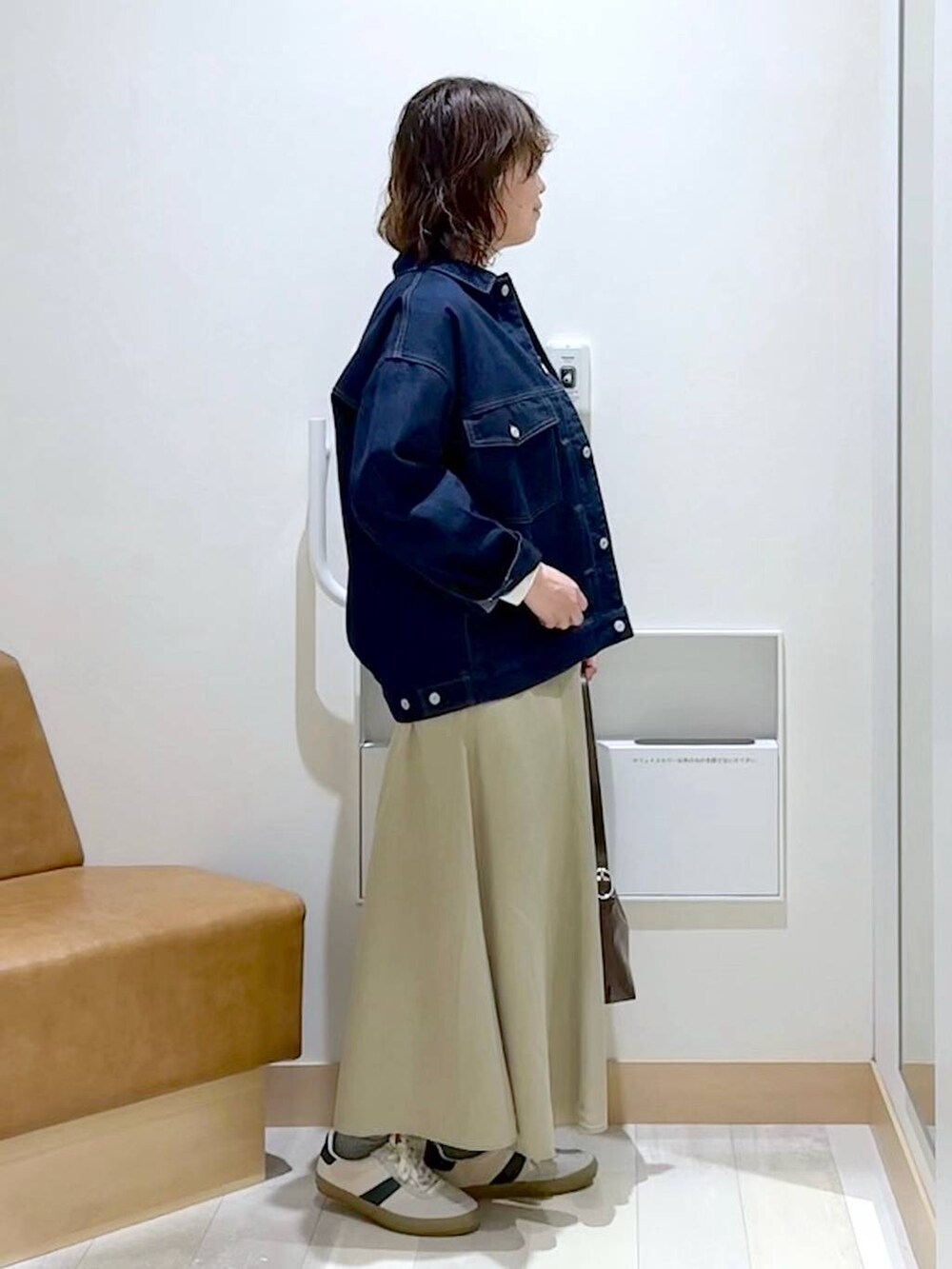 ベージュ系のスニーカー、ブラウン系のショルダーバッグ、ブルー系のデニムジャケットを着用したレディースの春コーディネートの3枚目の写真