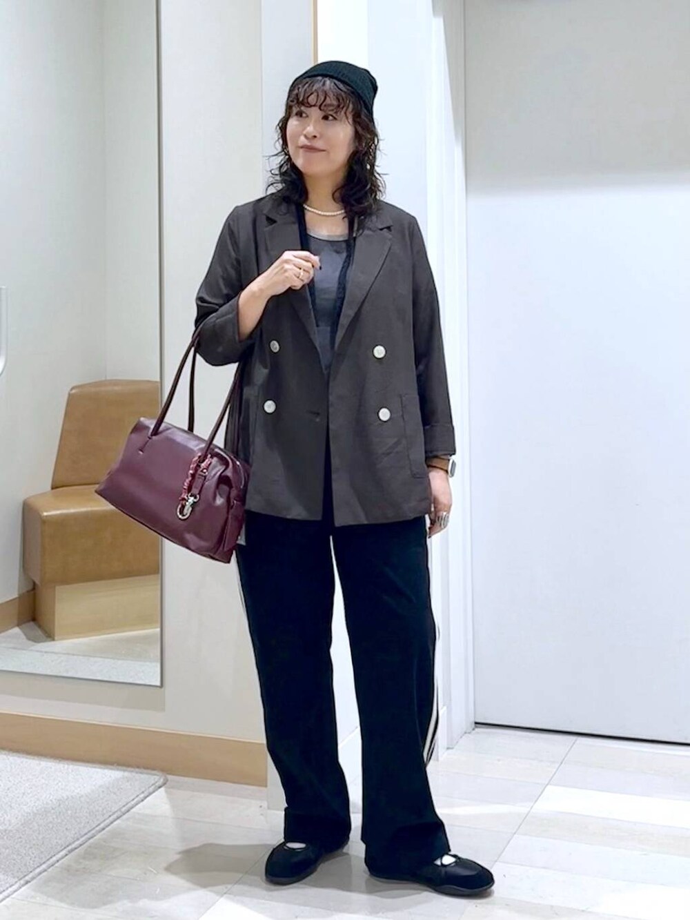 レッド系のボストンバッグ、ブラウン系のテーラードジャケット、グレー系のタンクトップを着用したレディースの秋コーディネートの2枚目の写真