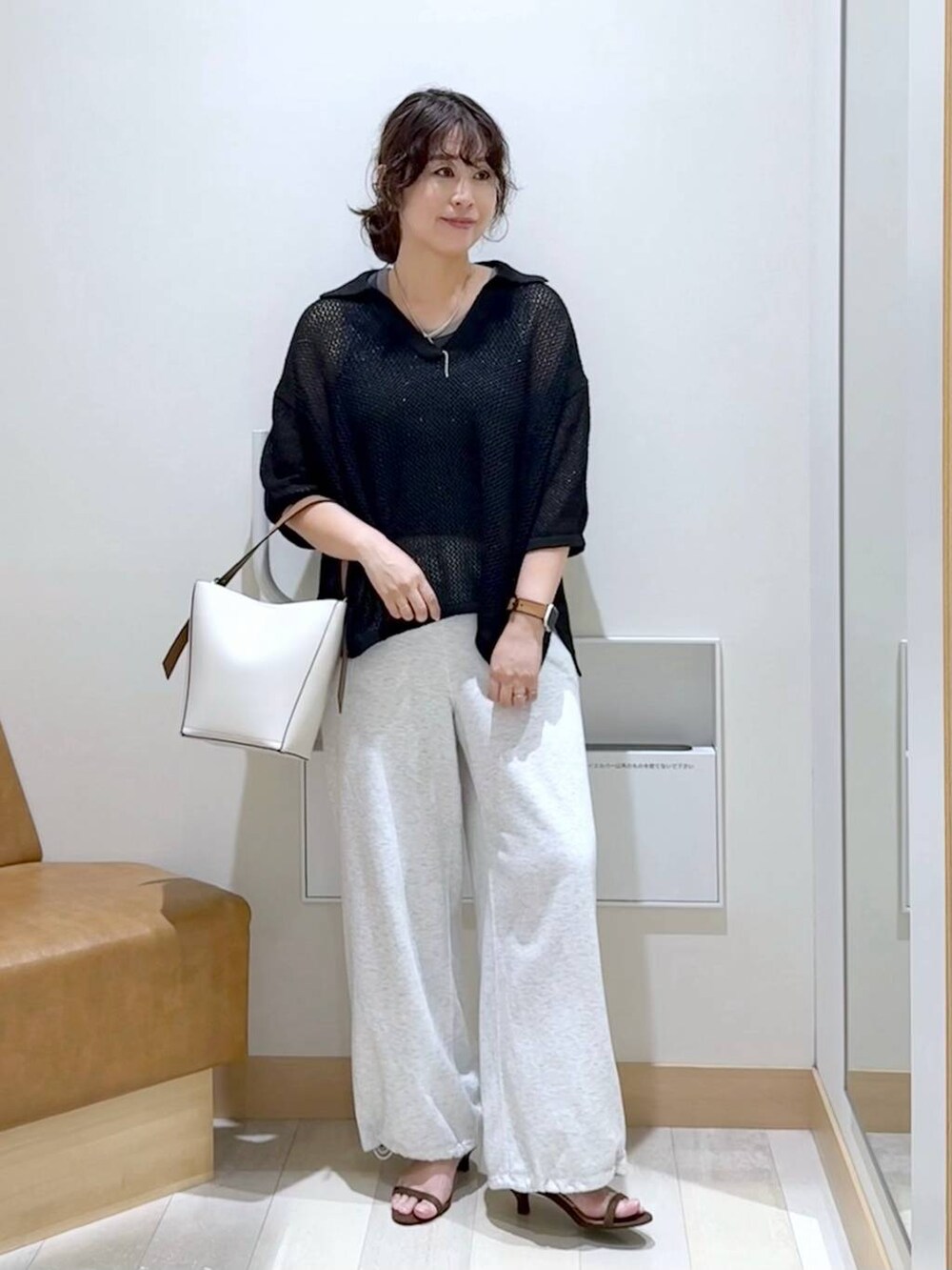 ホワイト系のショルダーバッグ、グレー系のスウェットパンツ、ブラウン系のサンダルを着用したレディースの夏コーディネートの2枚目の写真