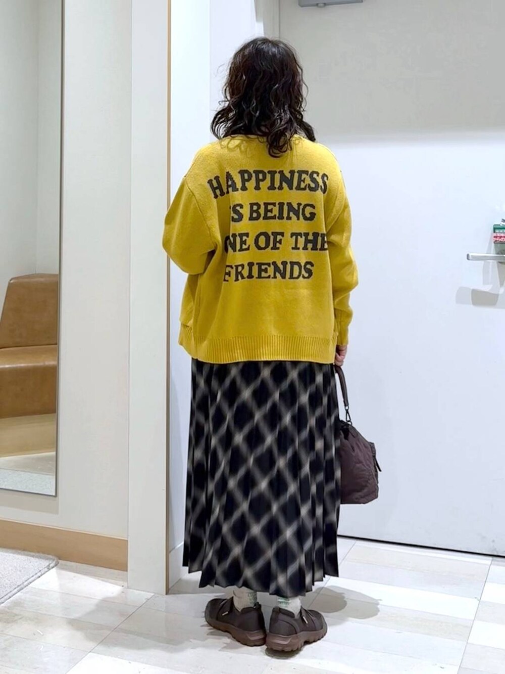 ブラウン系のスニーカー、ベージュ系のニット/セーター、ブラウン系のショルダーバッグを着用したレディースの秋コーディネートの4枚目の写真