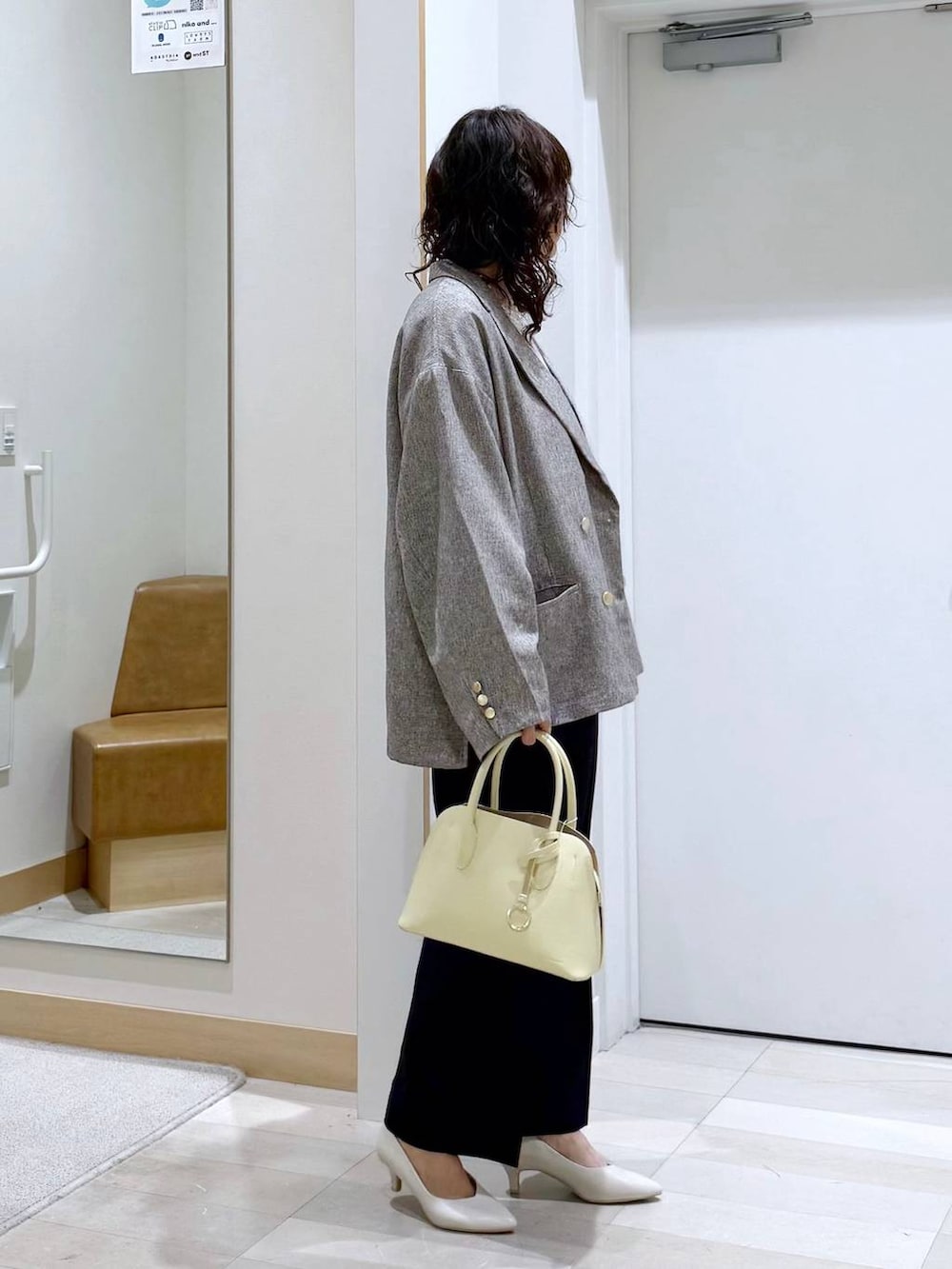 イエロー系のショルダーバッグ、ホワイト系のパンプス、ブルー系のセットアップを着用したレディースの春コーディネートの3枚目の写真