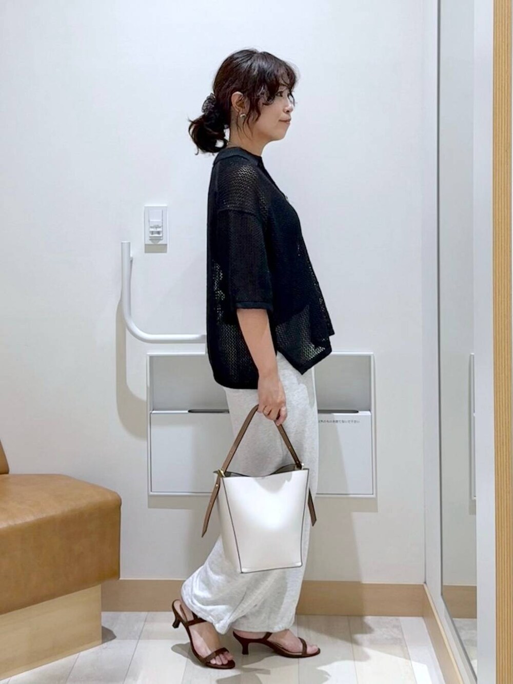 ホワイト系のショルダーバッグ、グレー系のスウェットパンツ、ブラウン系のサンダルを着用したレディースの夏コーディネートの3枚目の写真