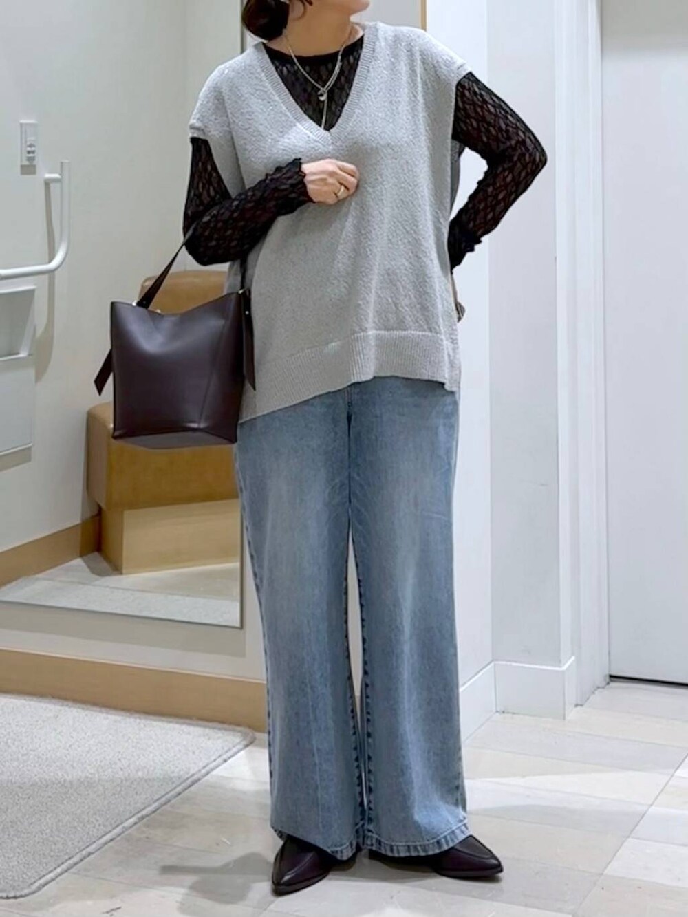 ブラウン系のショルダーバッグ、ブルー系のデニムパンツ、グレー系のベストを着用したレディースの秋コーディネートの5枚目の写真
