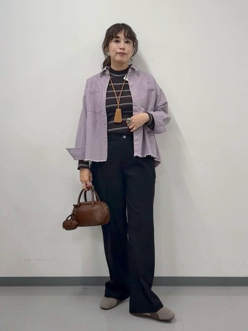 ブラウン系のニット/セーター、ブラック系のその他パンツ、ブラウン系のハンドバッグを着用したレディースの春コーディネートの2枚目の写真