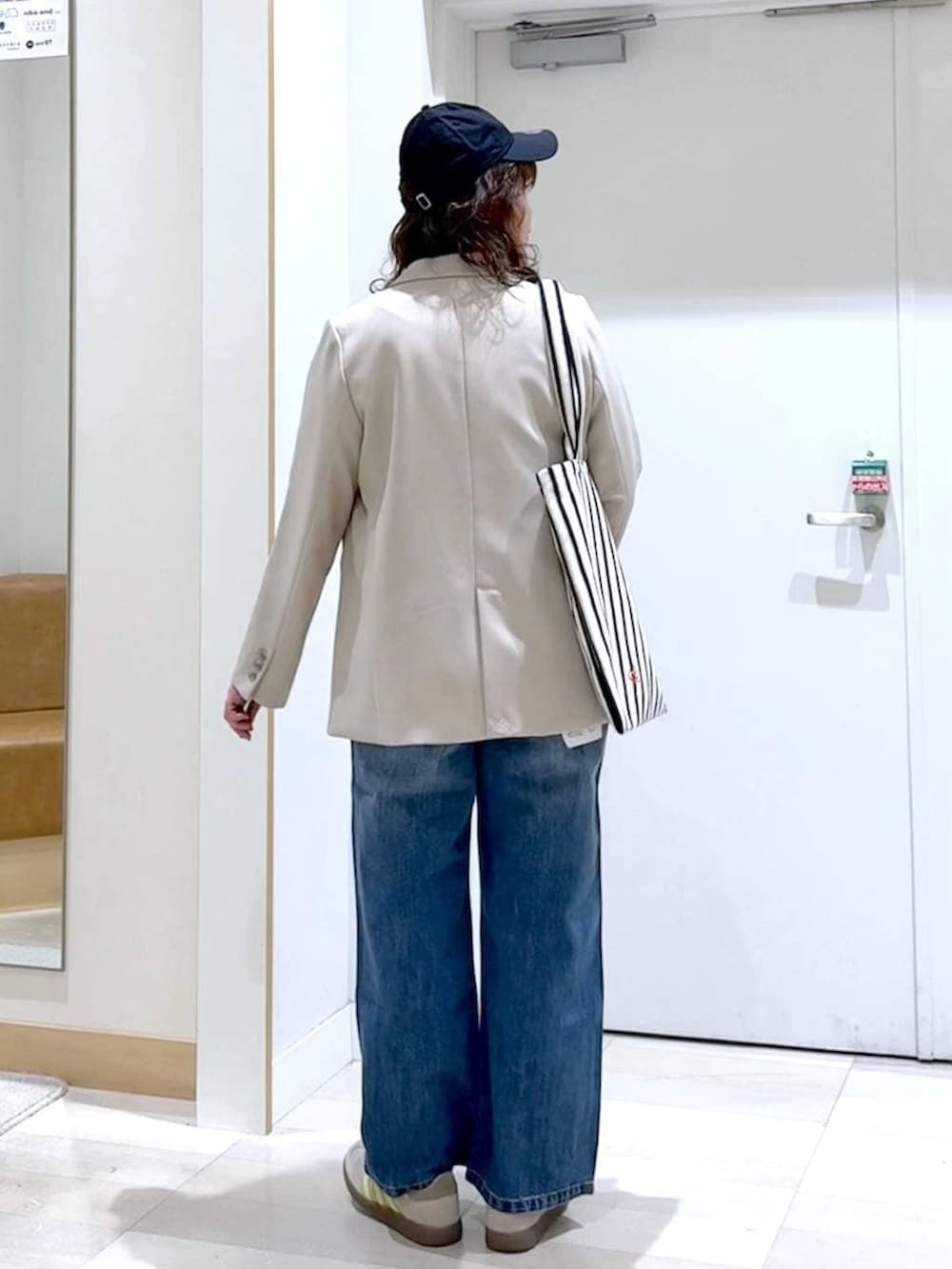 ブルー系のデニムパンツ、ベージュ系のテーラードジャケット、ホワイト系のトートバッグを着用したレディースの春コーディネートの4枚目の写真