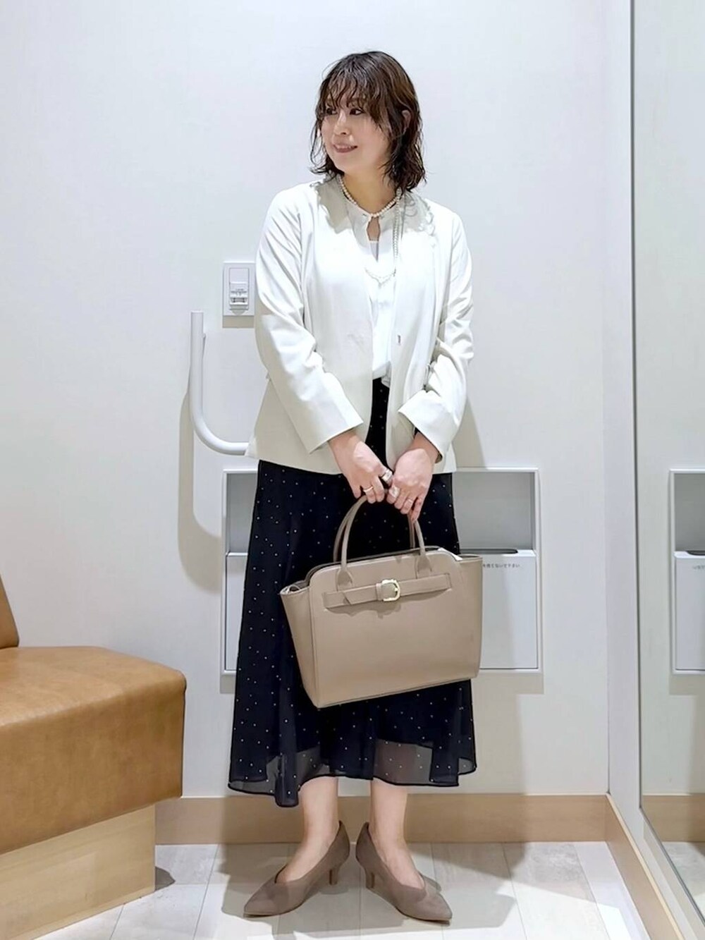 ホワイト系のノーカラージャケット、ホワイト系のシャツ/ブラウス、ベージュ系のパンプスを着用したレディースの春コーディネートの2枚目の写真