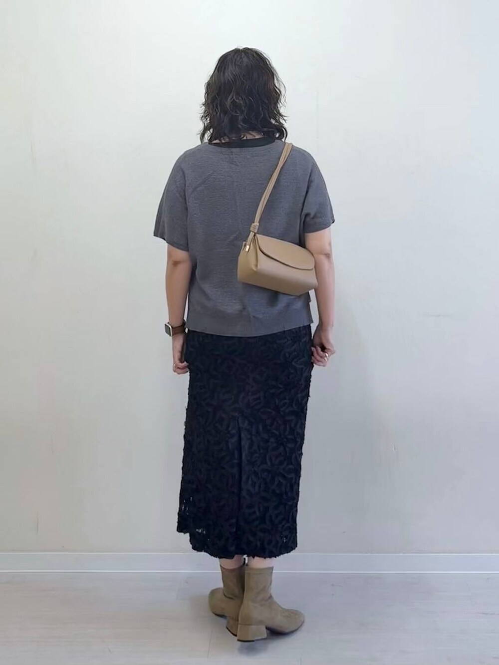 グレー系のニット/セーター、ベージュ系のショルダーバッグ、ブラック系のスカートを着用したレディースの夏コーディネートの4枚目の写真