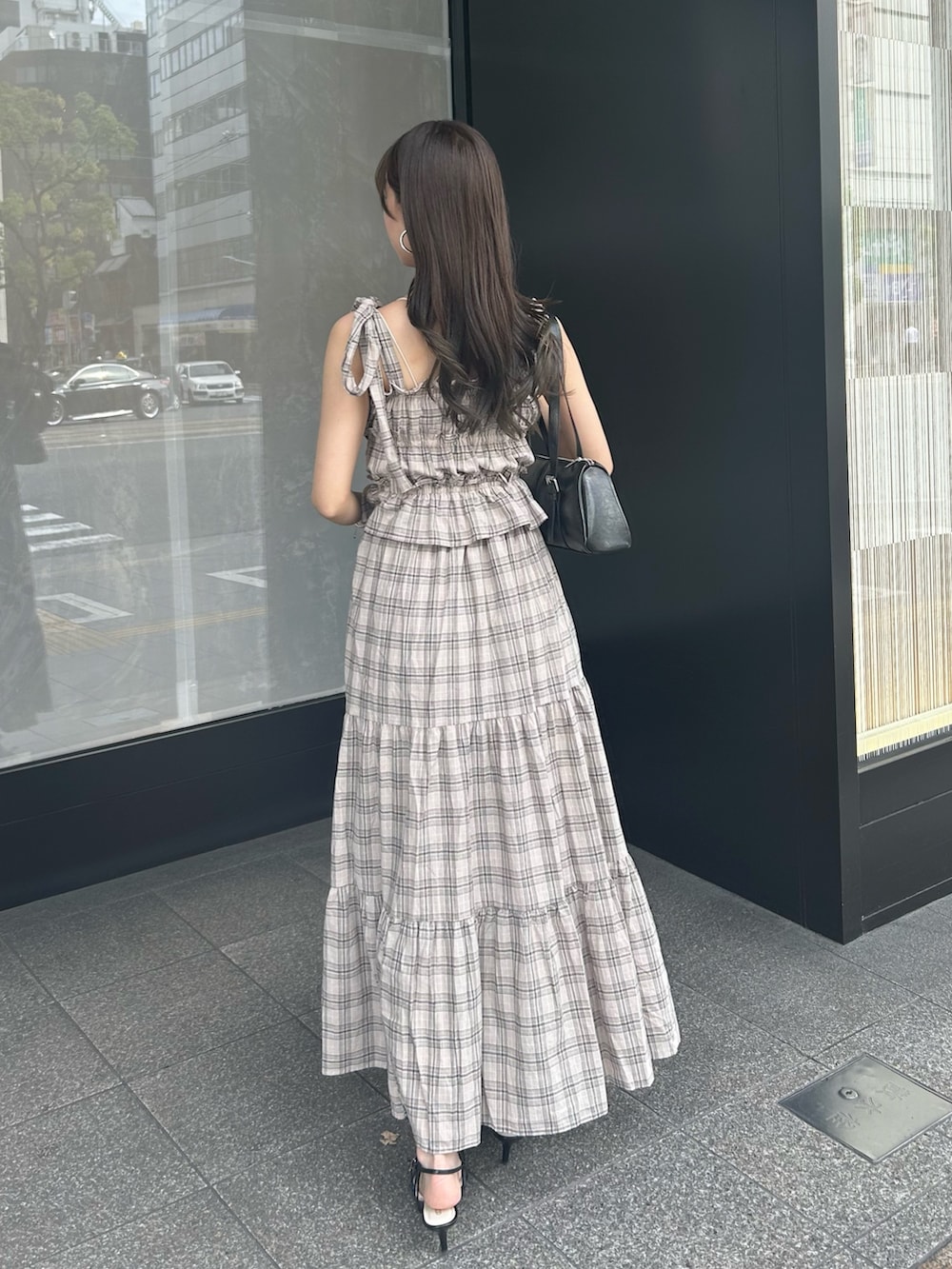 ベージュ系のワンピース、ブラック系のボストンバッグ、ブラック系のサンダルを着用したレディースの夏コーディネートの3枚目の写真