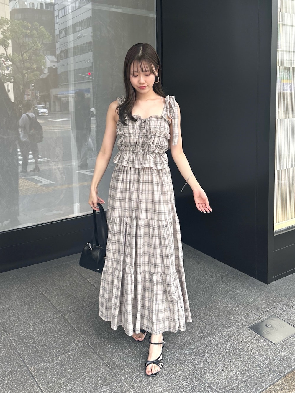 ベージュ系のワンピース、ブラック系のボストンバッグ、ブラック系のサンダルを着用したレディースの夏コーディネートの2枚目の写真