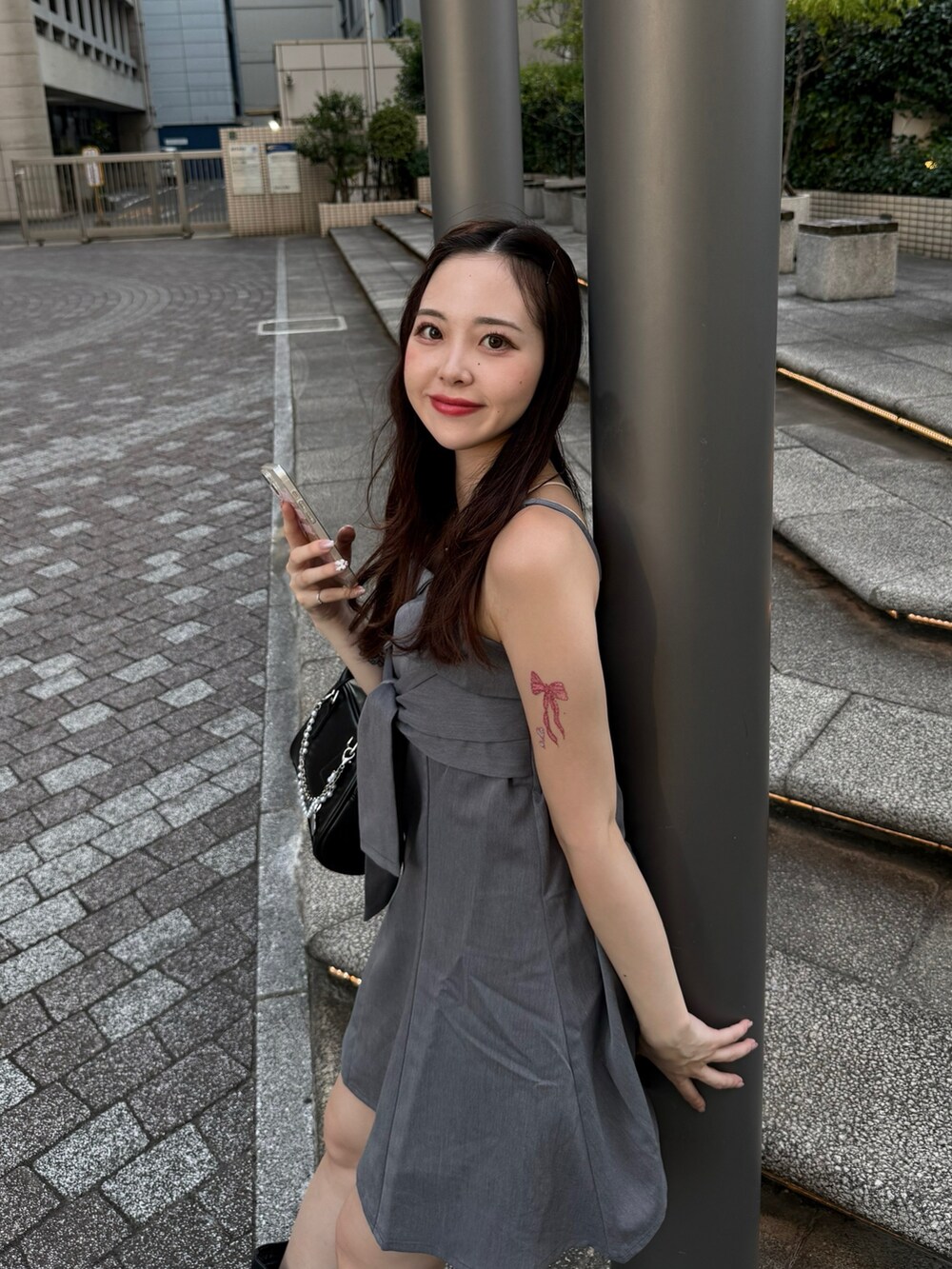 グレー系のワンピース、ブラック系のボストンバッグ、ブラック系のブーツを着用したレディースの夏コーディネートの3枚目の写真