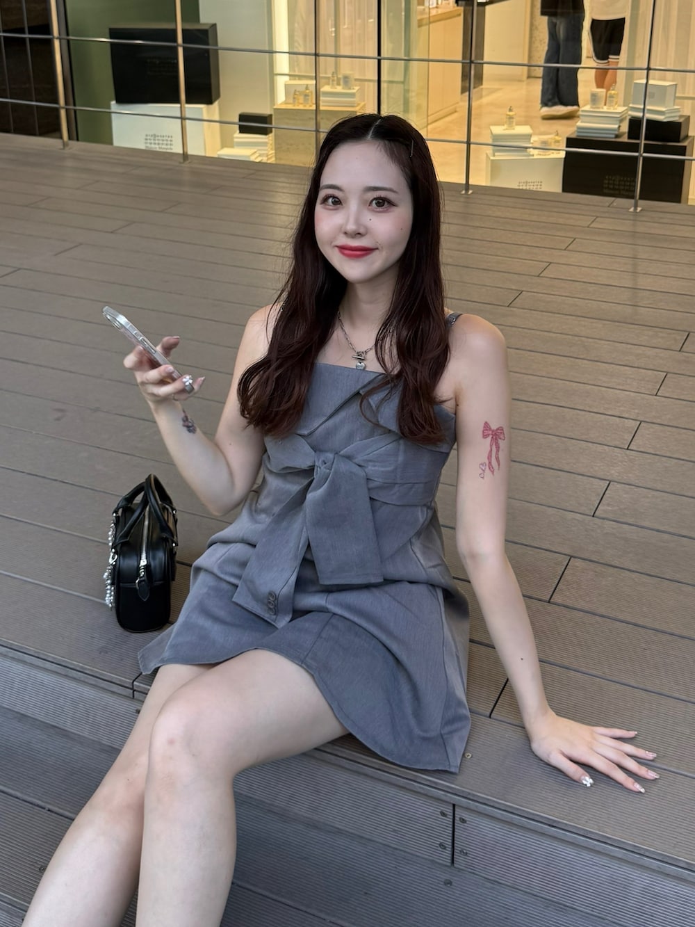 グレー系のワンピース、ブラック系のボストンバッグ、ブラック系のブーツを着用したレディースの夏コーディネートの4枚目の写真