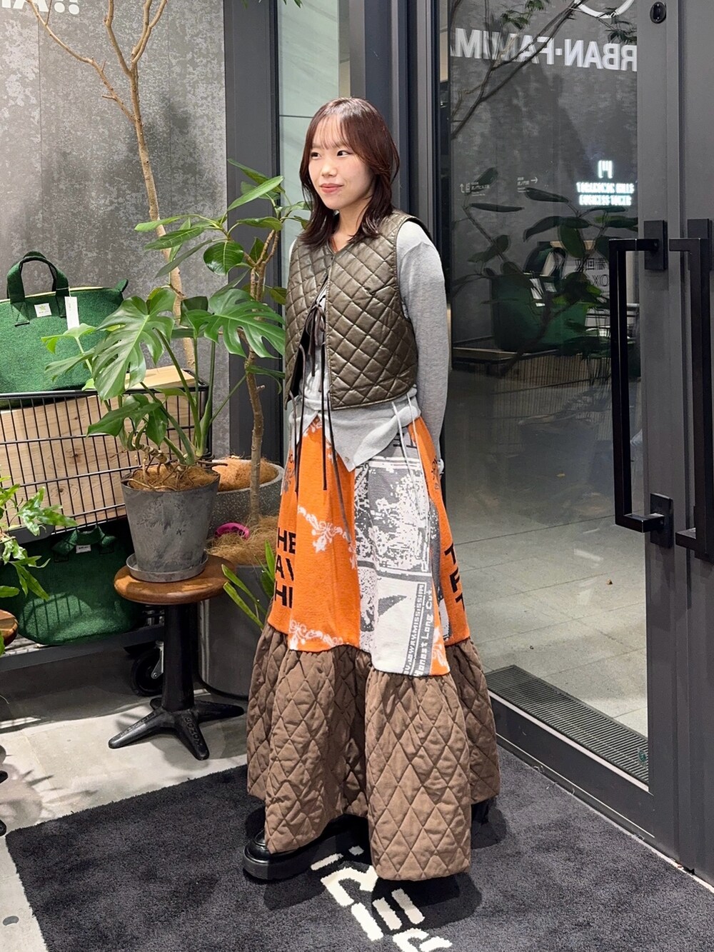 グレー系のカーディガン/ボレロ、オレンジ系のスカートを着用したレディースの冬コーディネートの2枚目の写真