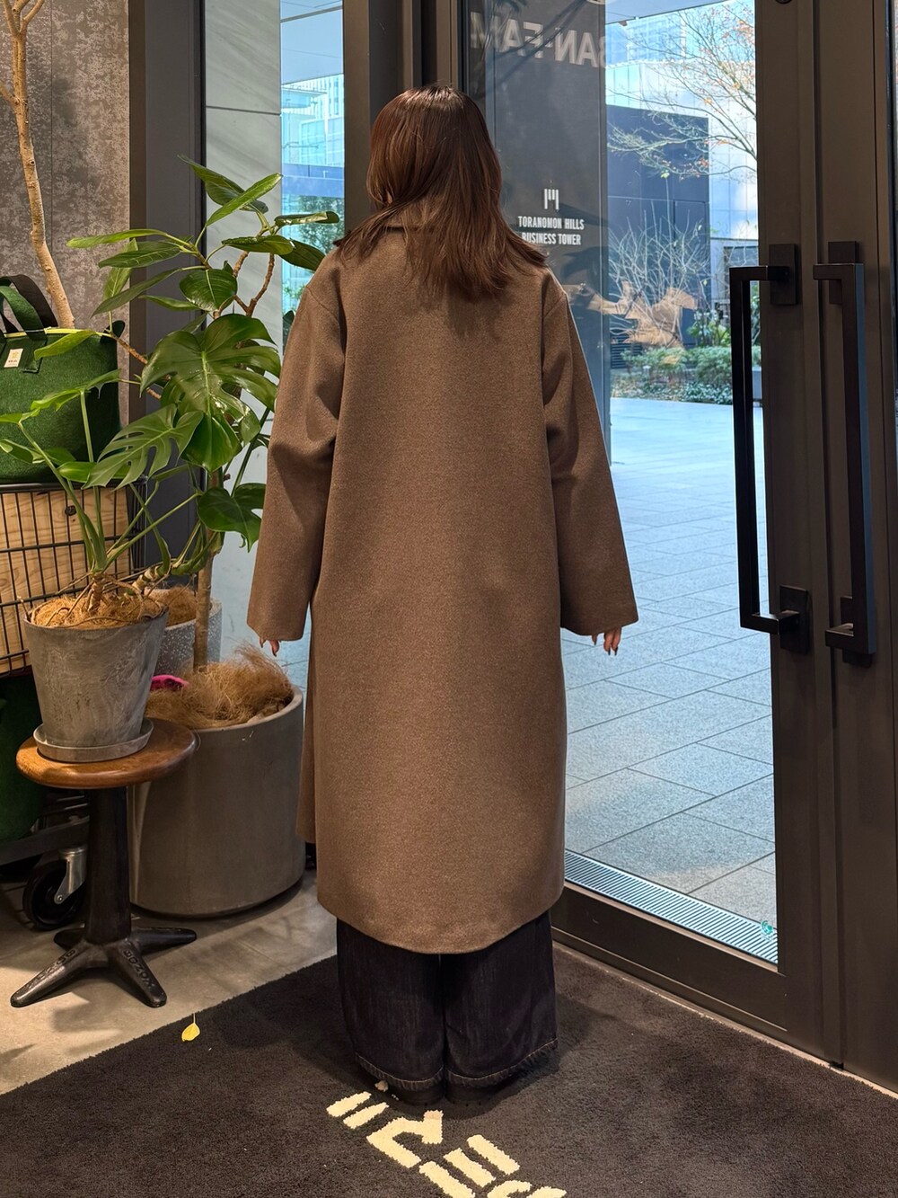 ブラウン系のその他アウター、グリーン系のニット/セーター、ブラック系のブーツを着用したレディースの冬コーディネートの2枚目の写真