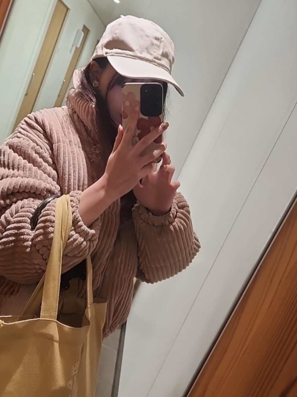 ピンク系のダウンジャケット/コート、ブラック系のパンツ、ホワイト系のキャップを着用したレディースの春コーディネートの2枚目の写真